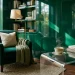 A luxurious reading nook featuring a glossy emerald green wall, velvet armchair, and acrylic side table catching the sunlight.