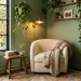 Serene sage cozy reading nook with a plush armchair, brass sconce, and beautiful trailing plants.