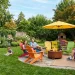 Wide view of a lush backyard featuring vibrant rainbow-colored patio furniture and a modern fire pit