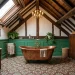 Luxurious Victorian attic bathroom featuring a copper tub and patterned encaustic floor tiles under a bright skylight.
