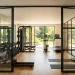 Bright home gym with black steel-framed glass partitions and modern workout equipment in natural sunlight.