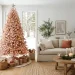 Soft blush pink Christmas tree decorated with natural wood bead garlands in a modern organic living room setting.