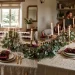 Beautifully styled holiday dining table featuring oatmeal linen tablecloth, burgundy napkins, and festive centerpieces