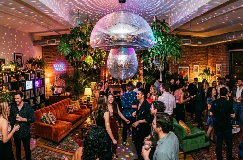 Wide view of a moody living room lit by a spinning mushroom disco ball hanging from the ceiling