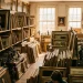 A sunlit room filled with stacked vintage paintings and antique decor at an estate sale