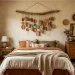 Earthy DIY clay wall hanging with terracotta moons and sage green leaves decorating a cozy bohemian bedroom wall.