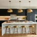 Modern kitchen interior featuring matte black cabinets and oversized brass dome pendant lights over a white marble island.