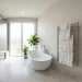 Luxurious master bathroom featuring a modern freestanding towel warmer holding white towels next to a glass shower