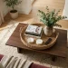 Styled living room coffee table featuring a woven seagrass tray organizing books, remotes, and plants.