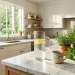 Elegant minimalist glass water pitcher with bamboo lid sitting on a bright marble kitchen counter in morning sunlight.