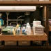 A beautifully organized deep under-sink cabinet featuring modern clear bins and sliding storage drawers.
